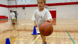 little kid playing basketball in gym