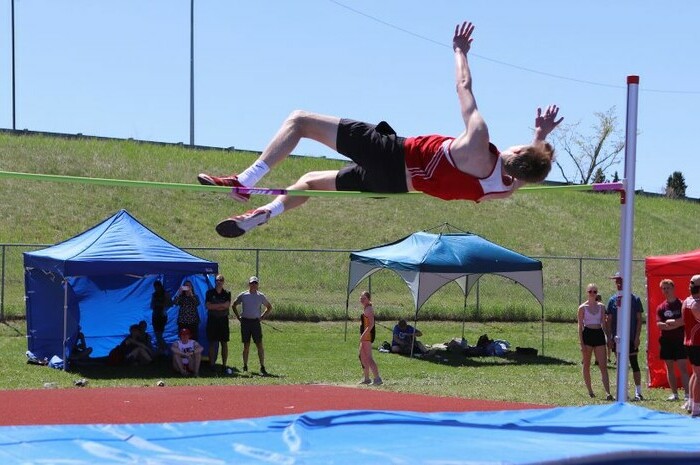 Male student competing in high jump event