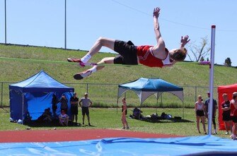 Male student competing in high jump event